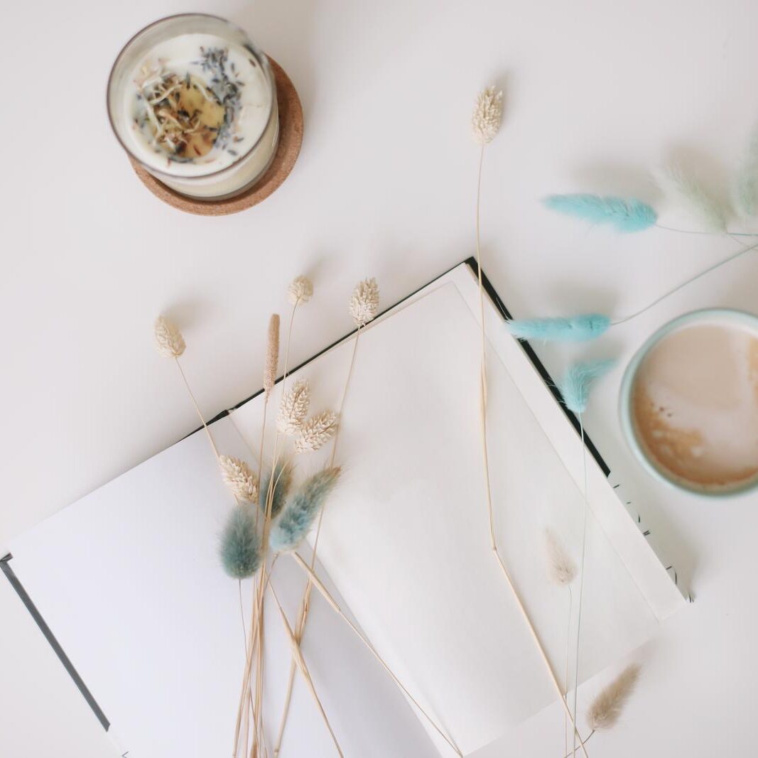 Blank paper sheet, coffee cup and dry flowers on white background. Minimal home workspace desk table. Flat lay, top view, mockup with copy space